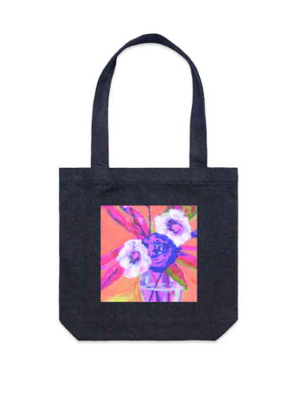 Black denim tote bag photographed against a white background, with a printed square panel showing an expressionist still life of pink and white flowers in a glass jar on a coral background.