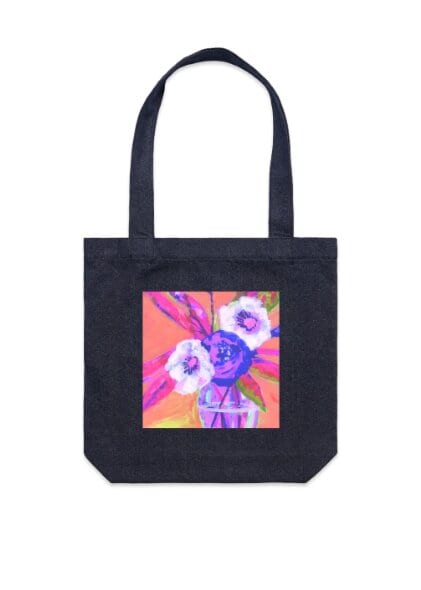 Black denim tote bag photographed against a white background, with a printed square panel showing an expressionist still life of pink and white flowers in a glass jar on a coral background.
