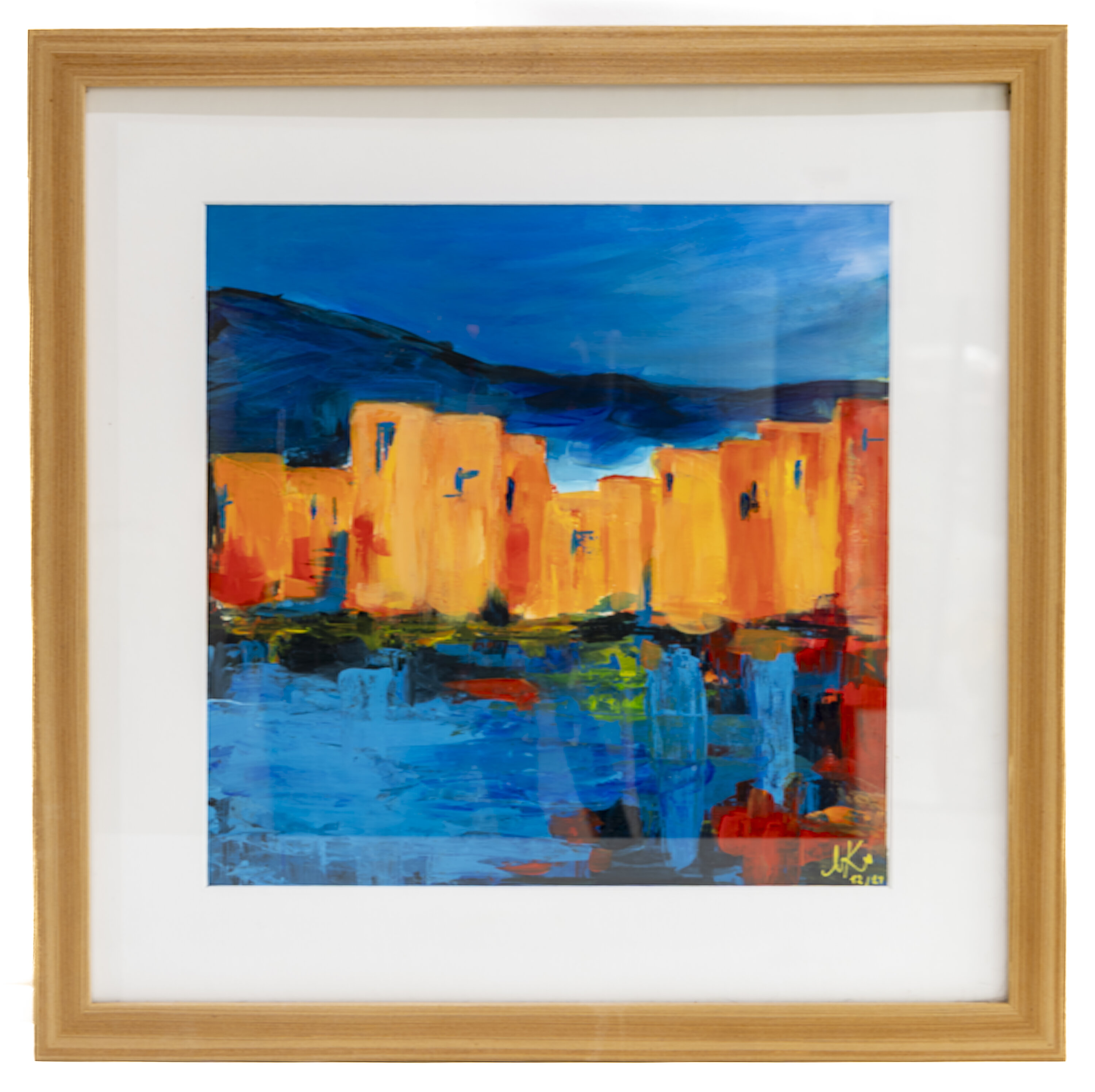 Expressionist landscape painting of a coastal village with ochre and orange buildings against deep blue mountains and sky, with blue water in the foreground.