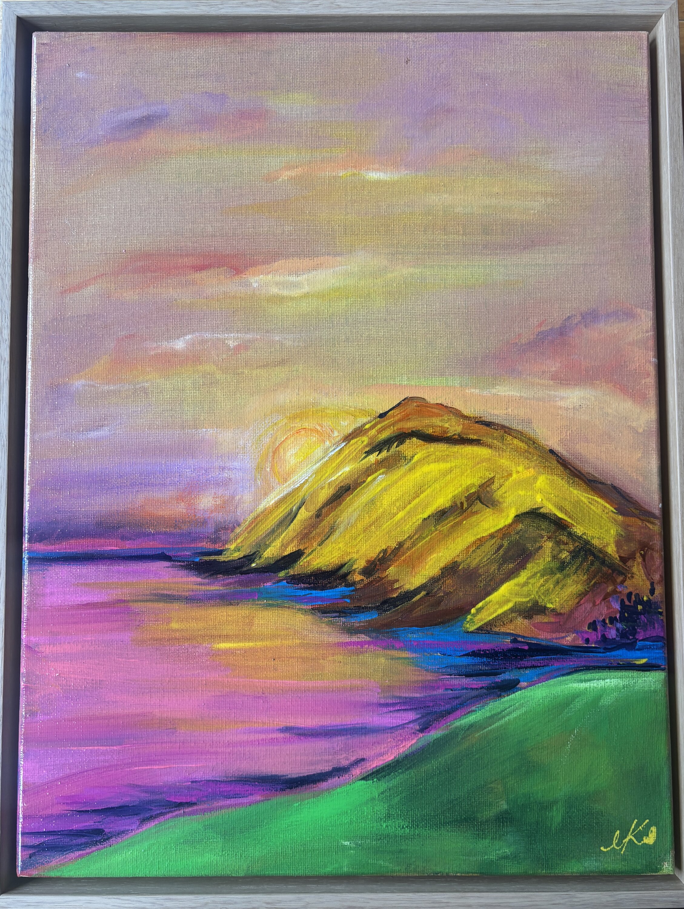 Landscape painting of a glowing golden sun rising behind a yellow and ochre mountain peak, its light spilling onto magenta water and a vibrant green foreground hill, beneath a soft pink and lilac sky.