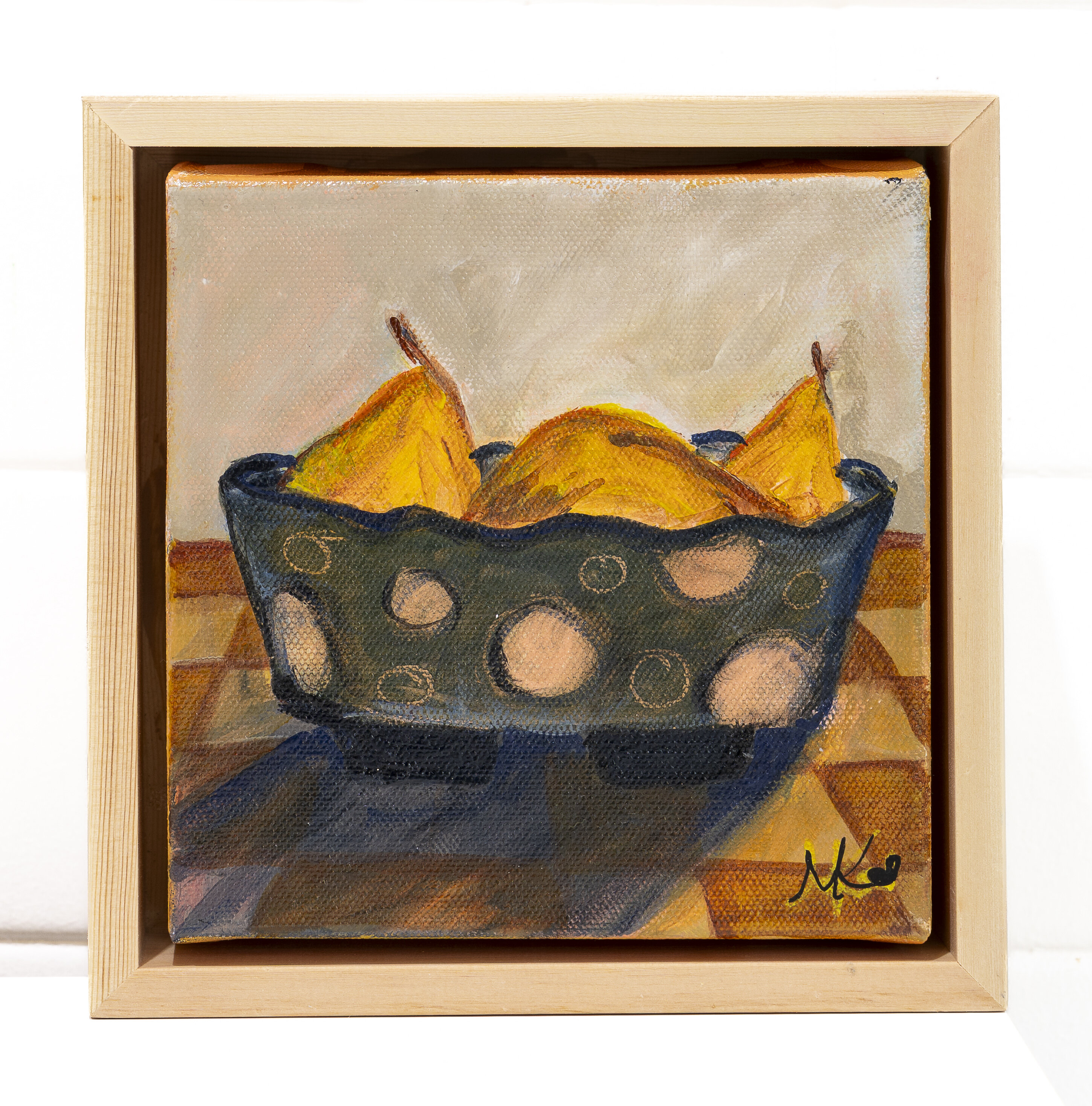 Still life painting of golden pears in a dark blue patterned bowl, on an orange and brown checkered tablecloth, against a neutral background.