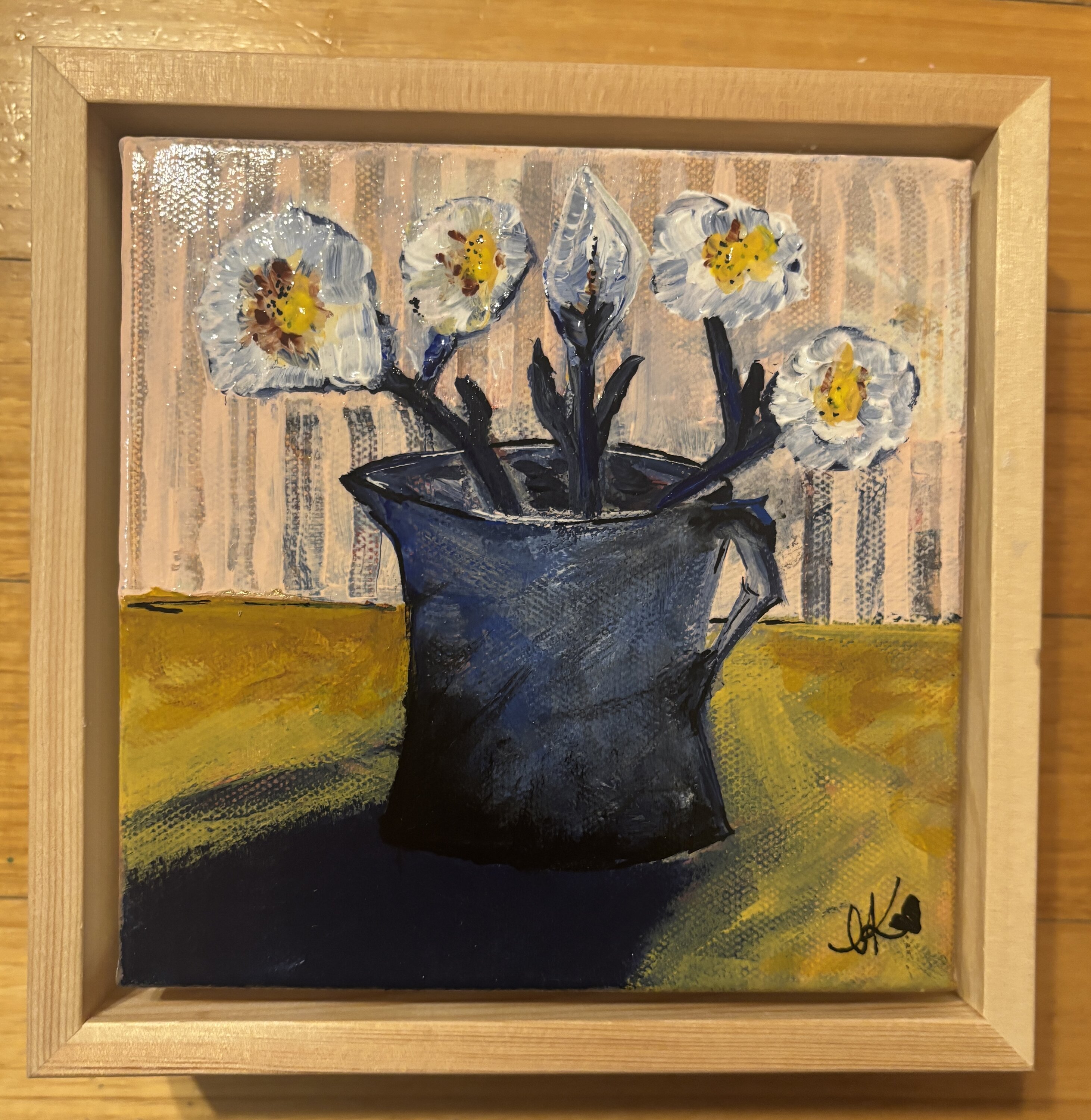 Framed still life painting of five cream and pale-blue daisies with yellow centres, arranged in a deep navy vase, on a mustard yellow table against a peach striped background.